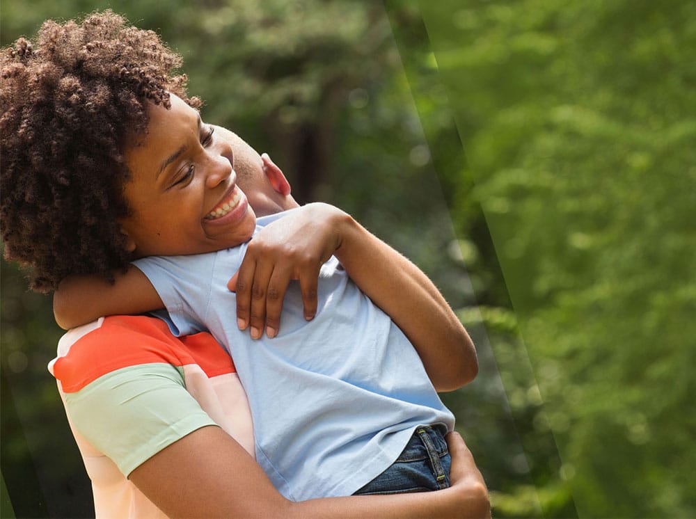 Mother clutching child and smiling in the sunlight.